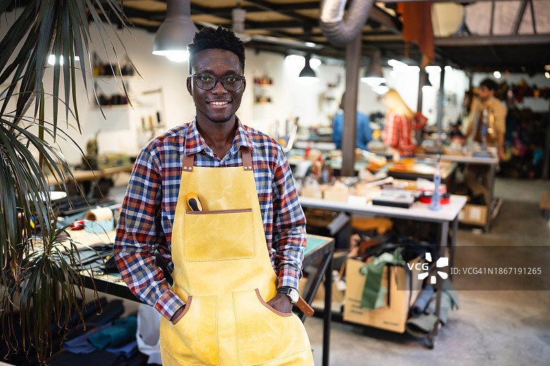 一个年轻的非裔美国男性裁缝在皮革车间工作的肖像图片素材