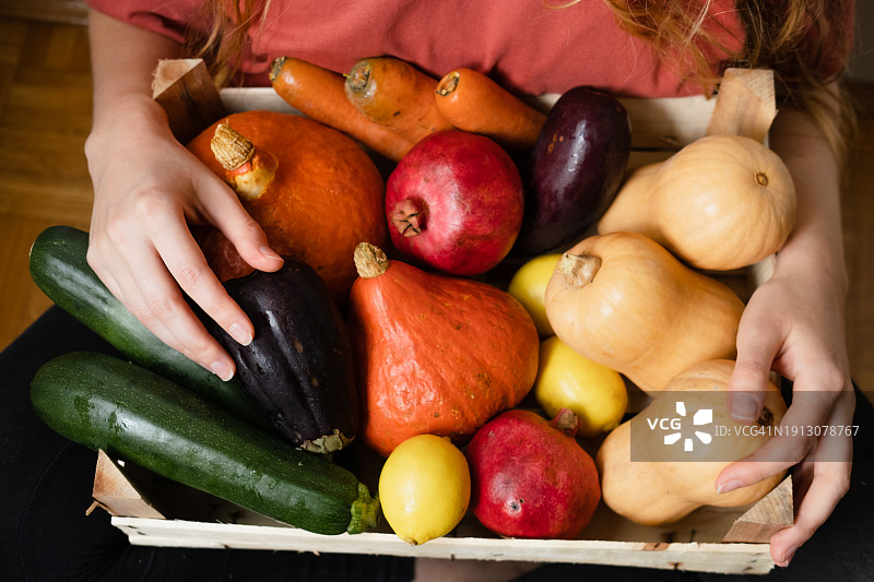 一名妇女拿着一盒色彩鲜艳的有机新鲜水果和蔬菜。图片素材