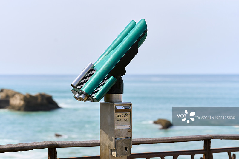 绿色瞭望望远镜在沙滩上的侧视图，背景是美丽的海景图片素材