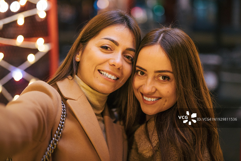 两名年轻女子站在街上用智能手机自拍图片素材