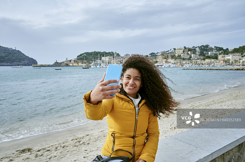 一名女子坐在沙滩边用手机自拍图片素材