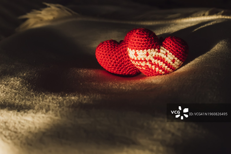 在温暖的毯子的背景上织着两颗红心。图片素材