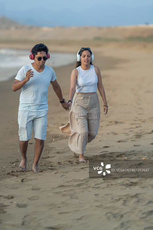 一对情侣手牵手在沙滩上奔跑图片素材