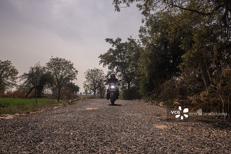 一个骑自行车的印度人穿过乡村公路，朝着镜头图片素材