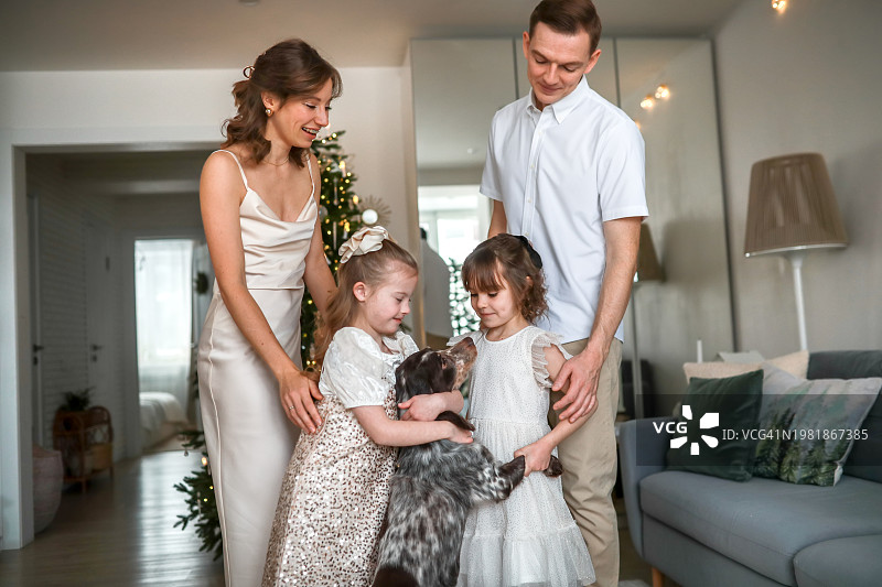 温馨的家庭时刻:与父母和两个女孩一起庆祝圣诞节。孩子和狗图片素材