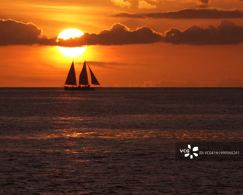 帆船的剪影在海上对橙色的天空，基韦斯特，佛罗里达州，美国图片素材