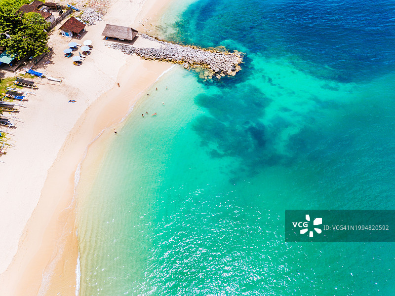 金色海岸线和绿松石般的海水:热带海滩与岩石码头的鸟瞰图。努沙杜瓦，巴厘岛。图片素材