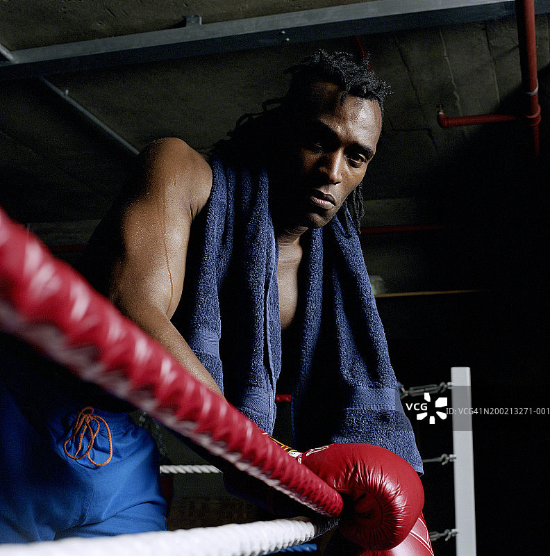 男拳击手脖子上围着毛巾，把手套放在绳子上，肖像图片素材