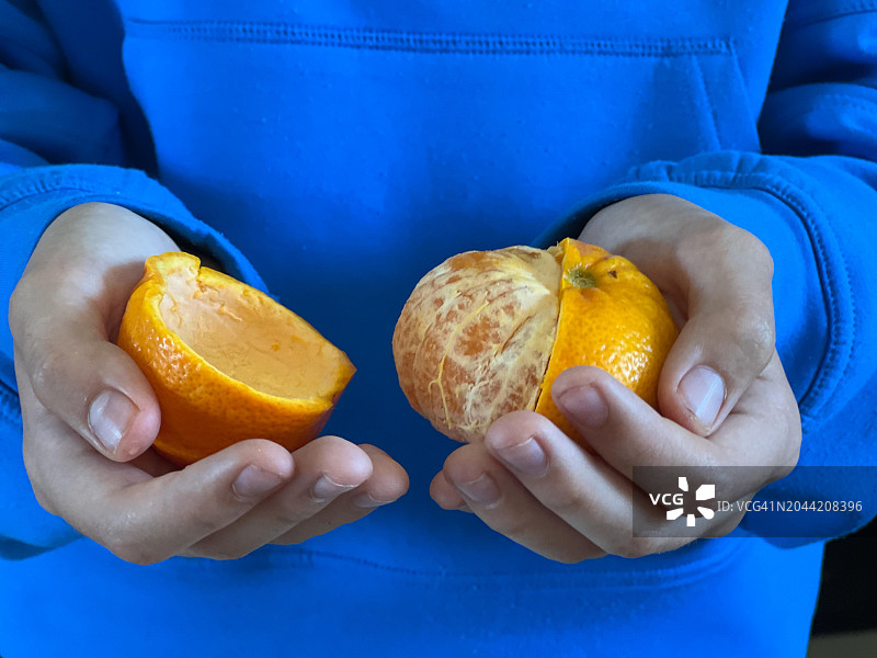 女孩用手拿着一个打开的橙子图片素材