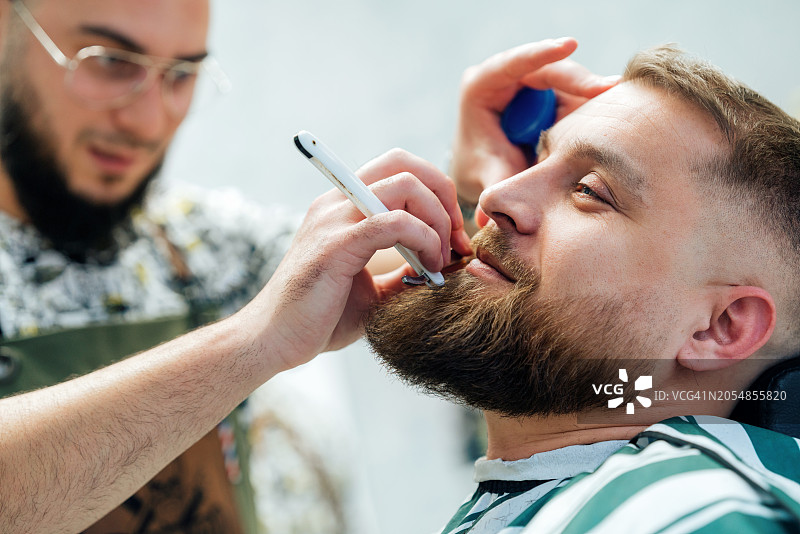 专业理发师在理发店为客户修剪胡须图片素材