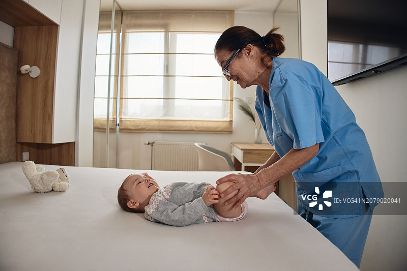 小婴儿接受骨科治疗，她的腿，以防止髋关节发育不良的儿科物理治疗师图片素材