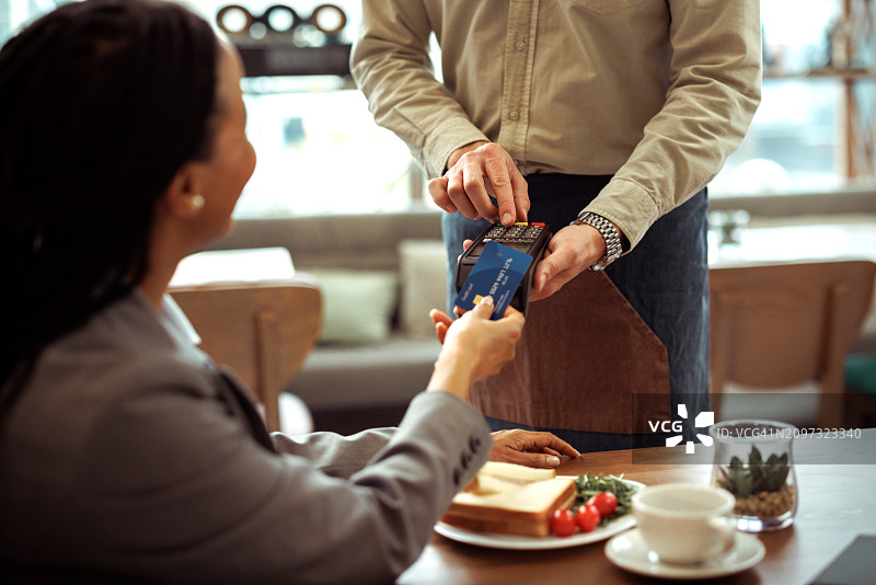 女商人用信用卡给餐馆服务员付款图片素材