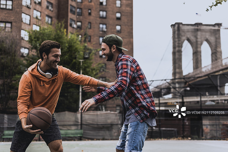 一个年轻人和朋友在城里的宫廷里打篮球图片素材