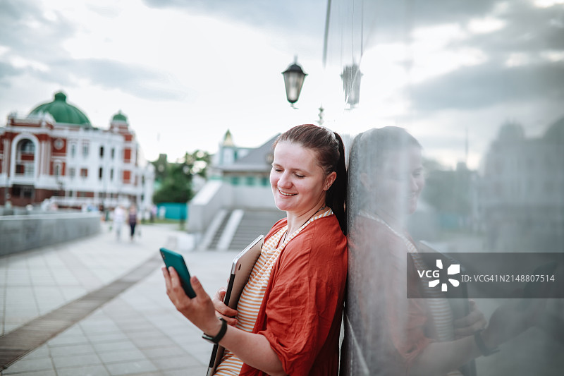 大码中年妇女在城市的混凝土堤岸边用智能手机发短信图片素材