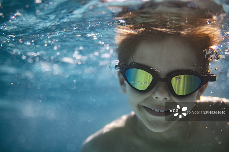 一个小男孩在游泳池里游泳的水下肖像。图片素材