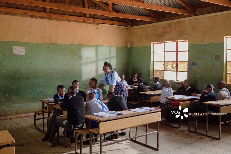 在非洲的一所农村学校，女教师与穿着校服的高中生进行小组讨论图片素材
