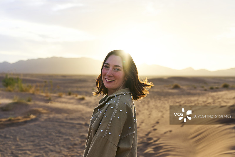 一个美丽的女人的肖像，微笑着转向相机站在萨戈拉沙漠，后视图图片素材