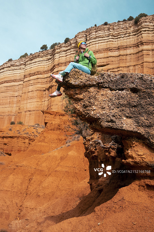 一个背着背包的成熟女人坐在红峡谷的岩石上图片素材