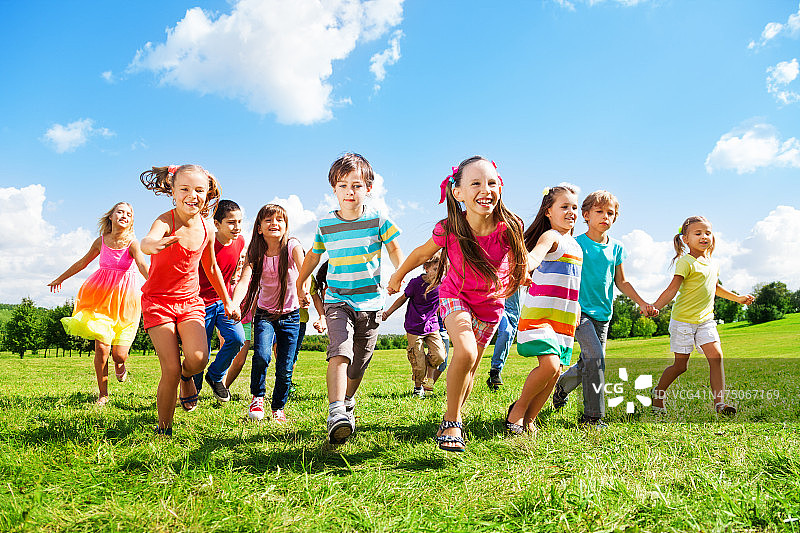在一个阳光明媚的日子里，一群孩子在草地上奔跑图片素材