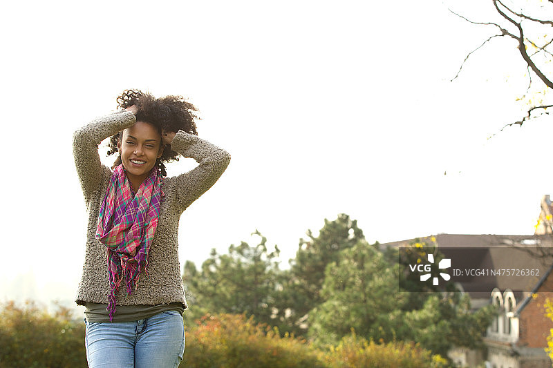 微笑的年轻非洲裔美国妇女，双手插着头发图片素材