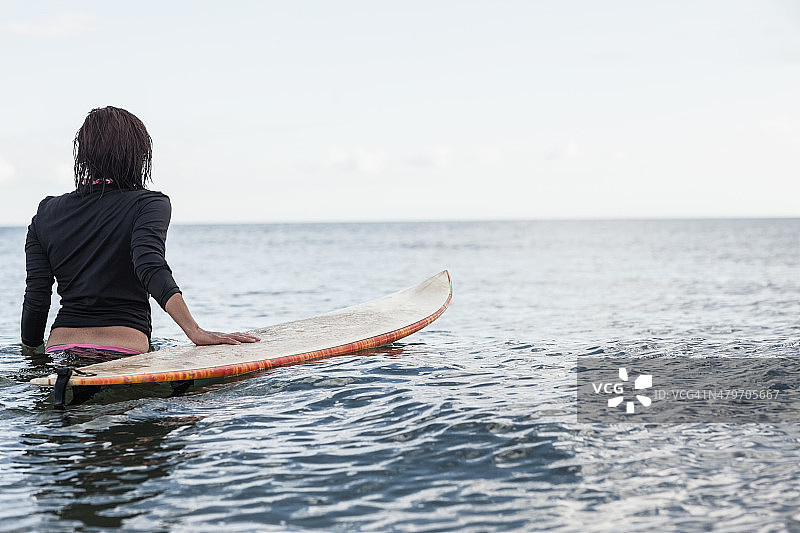 一个女人的后视图与冲浪板在水里图片素材