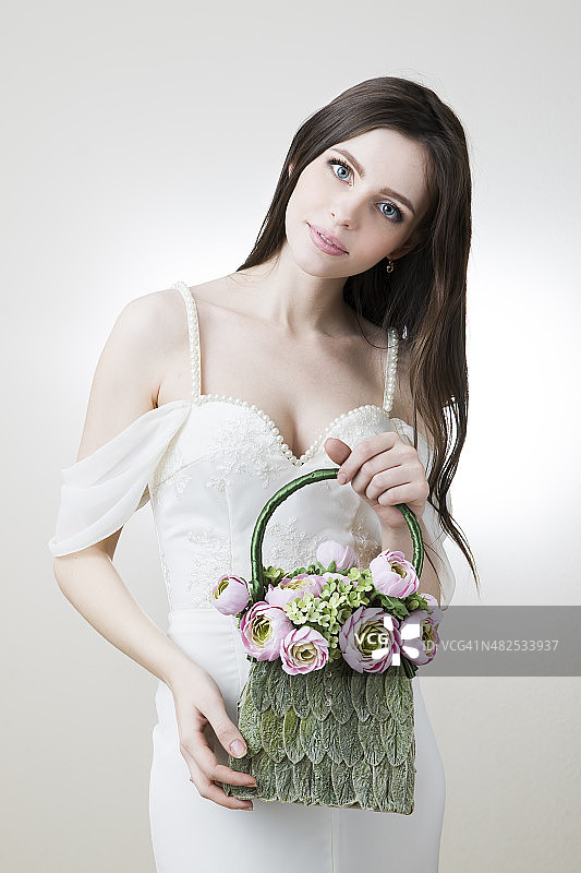 年轻漂亮的新娘，手里拿着手提包图片素材