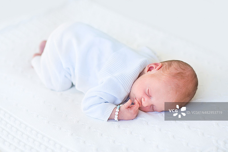 可爱的新生婴儿趴在白色的毯子上睡觉图片素材