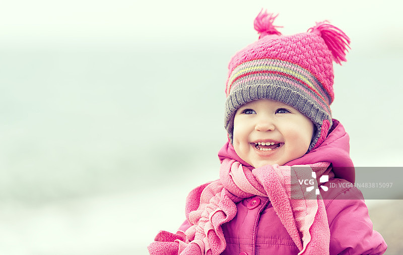 快乐的小女孩戴着粉色的帽子和围巾图片素材
