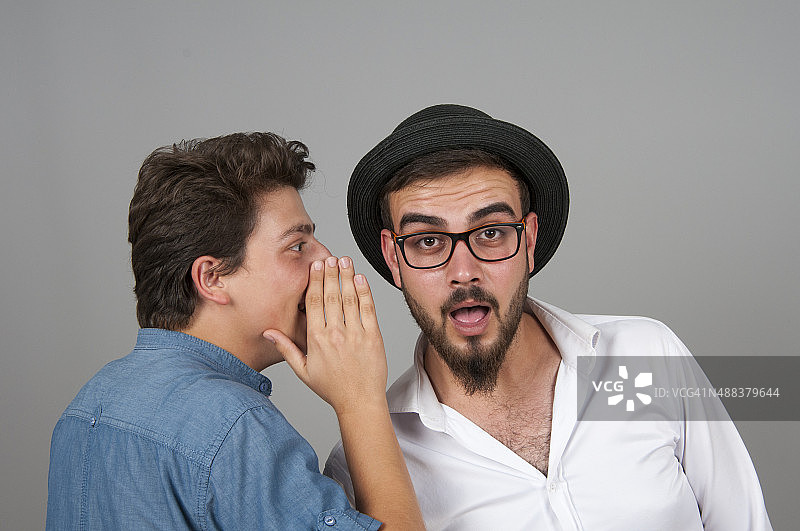 一个年轻人在他朋友耳边低语图片素材