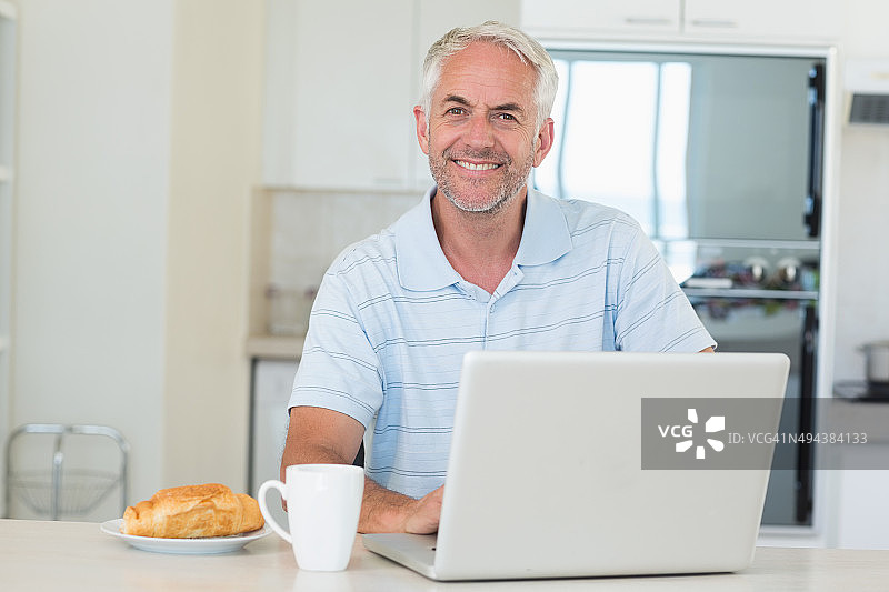 早餐时用笔记本电脑的快乐男人图片素材