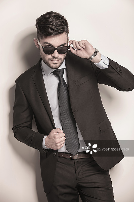男模特在西装和领带摘下他的太阳镜图片素材