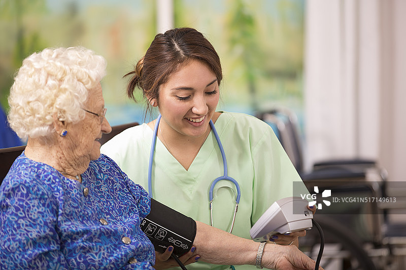 家庭保健护士检查老年妇女的血压。图片素材