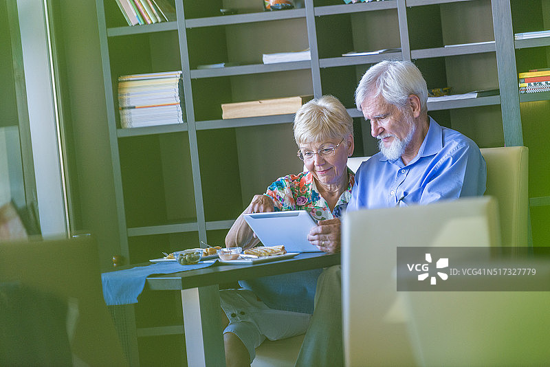 一对老年夫妇正在使用数码平板电脑，看起来很好奇图片素材