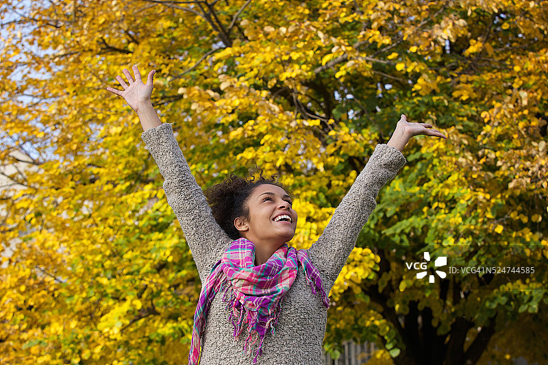 无忧无虑的年轻女子举起双臂享受秋天图片素材