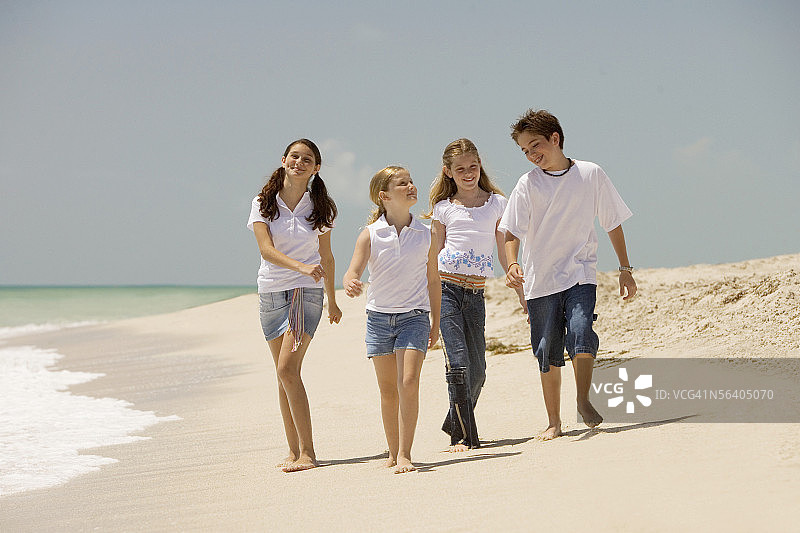 三个女孩和一个男孩在海滩上散步图片素材