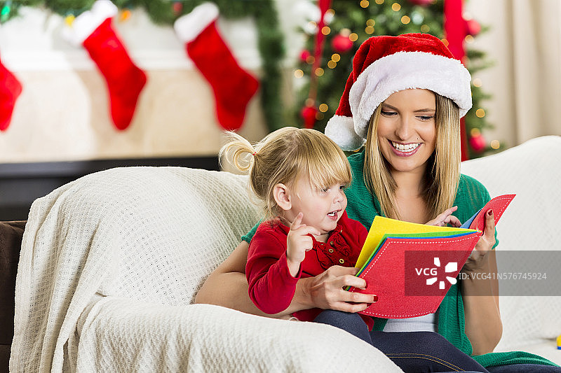 妈妈和女儿在圣诞节期间愉快地阅读图片素材