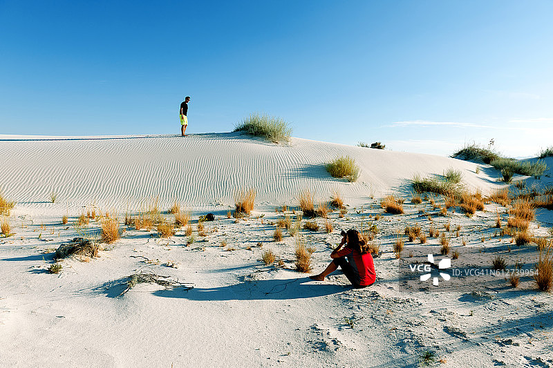 年轻女子拍摄朋友在地平线白沙，美国图片素材