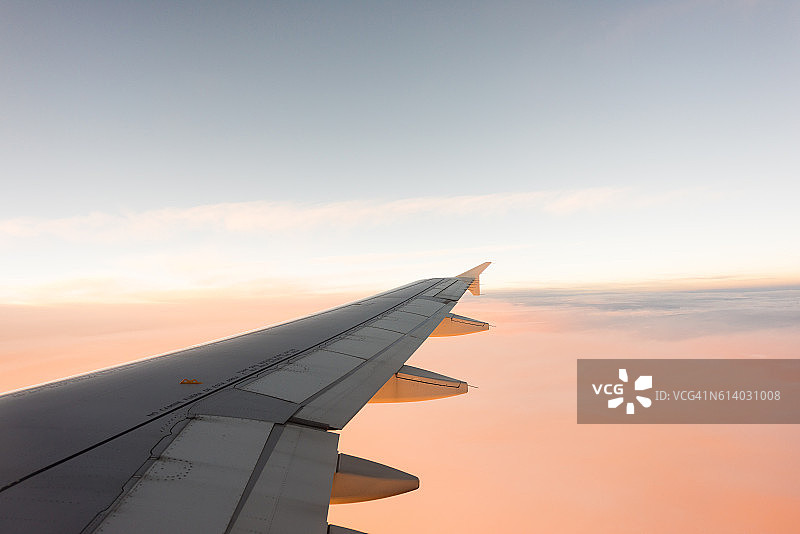 机翼的飞机在蓝色和粉红色的天空背景图片素材