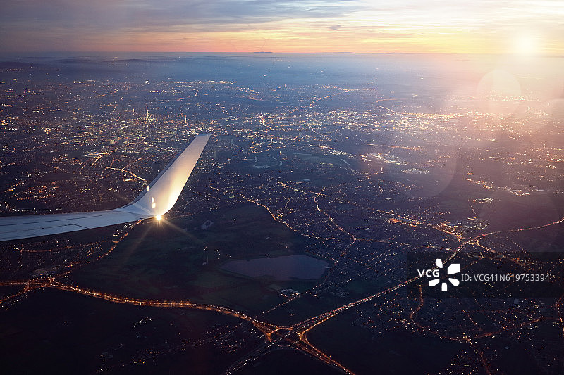 日落时从降落飞机窗口俯瞰城市图片素材