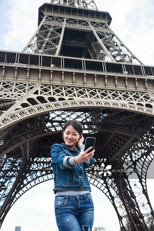 年轻的中国女游客站在埃菲尔铁塔前图片素材