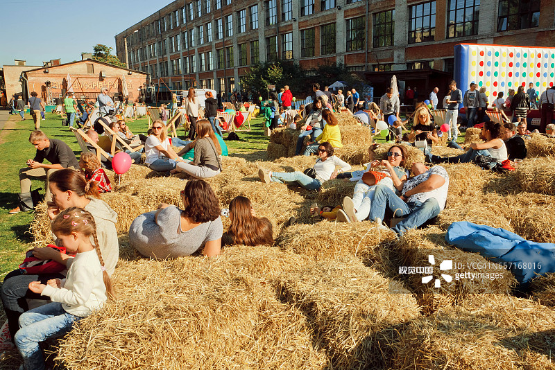 人们和年轻的家庭在户外城市节日的干草上放松图片素材
