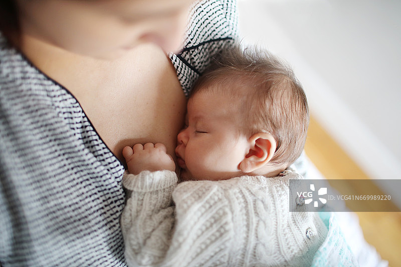 一个2个月大的女婴在她妈妈的怀里图片素材
