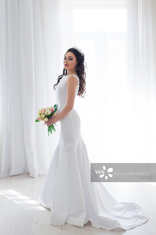 新娘身着白色婚纱，手持一束鲜花图片素材