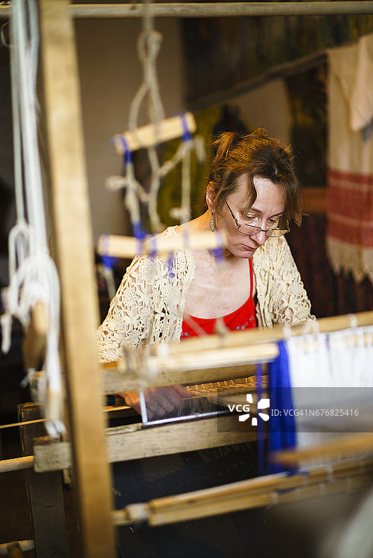 成熟的女人在古董织机上挥手。传统工艺品，白俄罗斯，东欧。图片素材