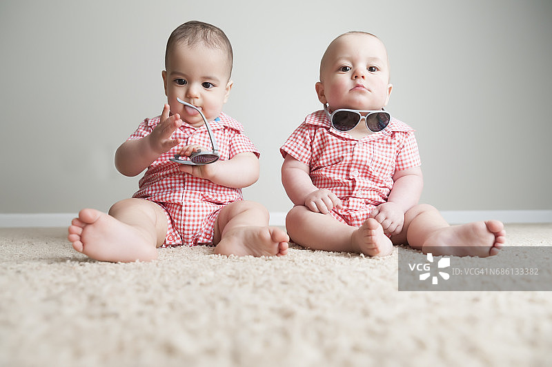 11个月大的双胞胎男孩戴着太阳镜一起玩图片素材