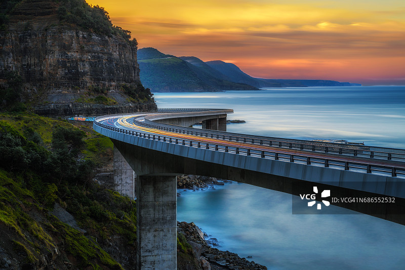日落在海上悬崖桥沿澳大利亚太平洋海岸与过往的汽车灯光图片素材
