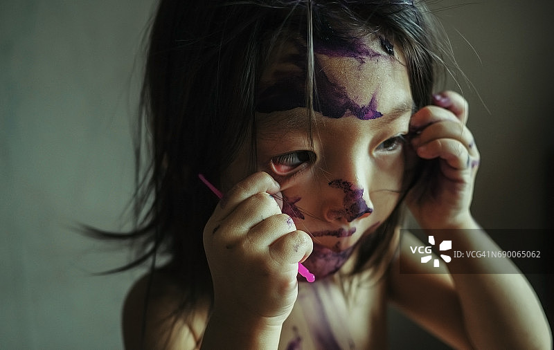 一个小女孩脸上画着鬼脸，扭曲着脸图片素材