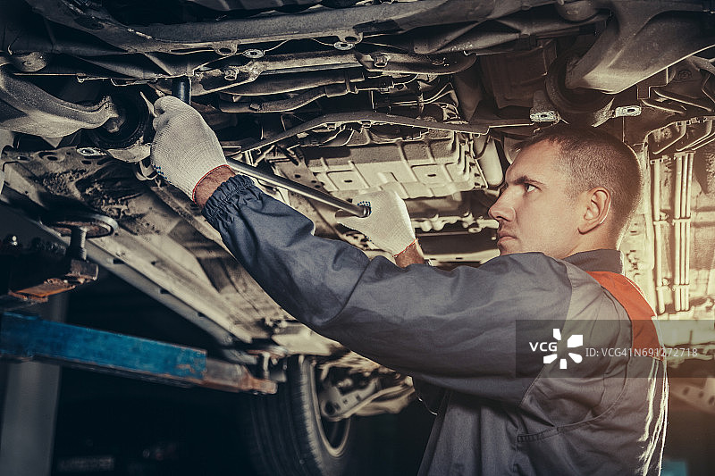 在汽车修理厂修理汽车的专业机械师图片素材