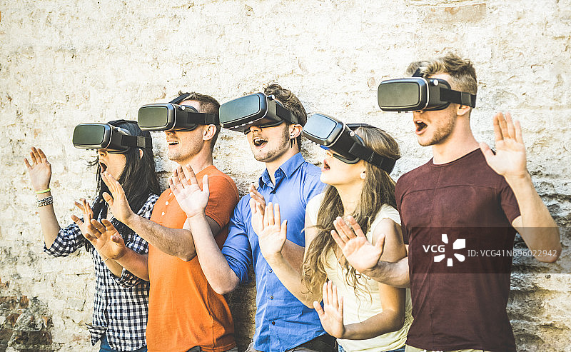 朋友群玩虚拟现实眼镜户外-虚拟现实和可穿戴的技术概念与年轻人有乐趣与耳机护目镜-数字一代趋势-复古对比滤镜图片素材