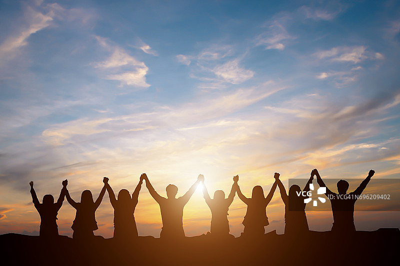 剪影快乐的企业团队在日落天空高手背景为企业团队合作的概念图片素材